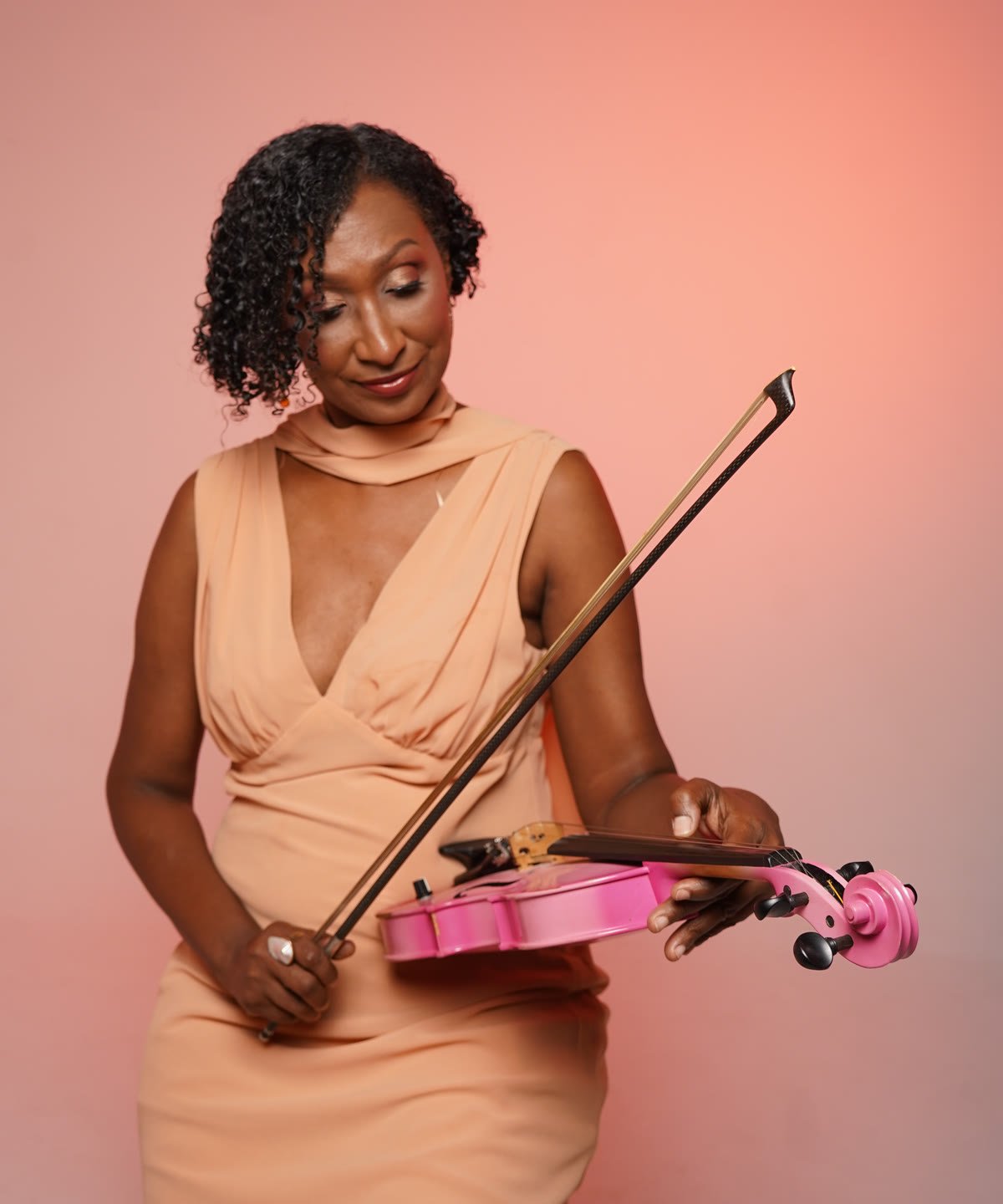 Melanie mirando con calma su violín rosado, con el arco en la mano