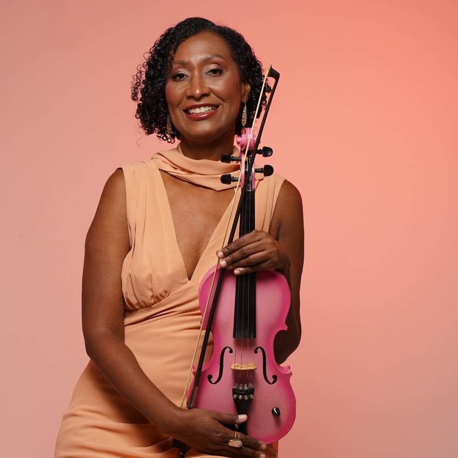 Melanie sonriendo con su violín electroacústico rosado entre las manos